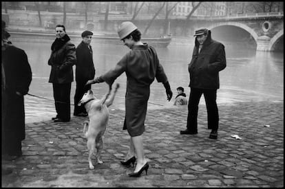 Una mujer juega con un perro en la orilla del Sena, en París en 1958.