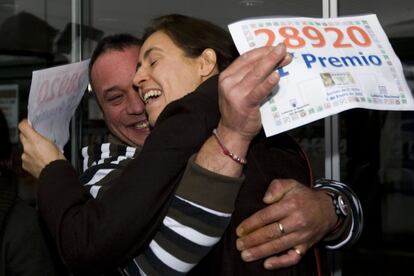 Carlos (i), uno de los agraciados con el primer premio en la lotería de El Niño gracias al número 28920, se abraza a la lotera que lo repartió, en Terrassa (Barcelona).