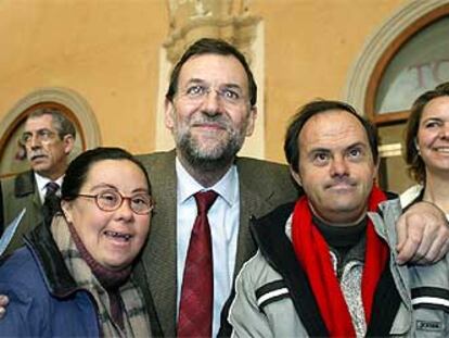 El candidato popular Mariano Rajoy se fotografía junto a dos personas con síndrome de Down.