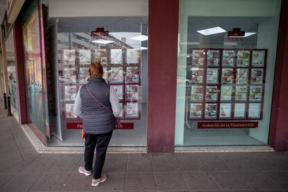 Una mujer mira anuncios de venta de pisos en el escaparate de una inmobiliaria en Sevilla.