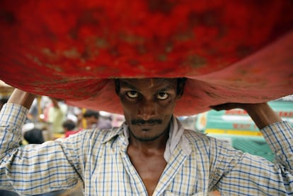 Un vendedor indo carga con un saco lleno de flores, en el mercado de Lucknow, India.