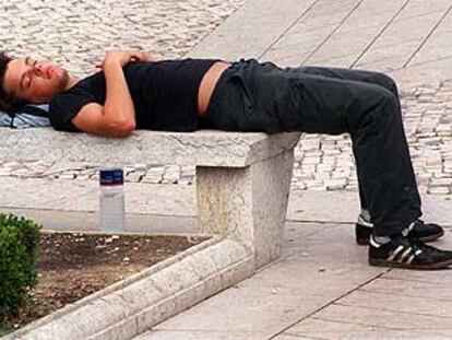 Un joven descansa del ajetreo de las fiestas de Bilbao sobre un banco de piedra de la plaza Moyúa, como si de un colchón de plumas se tratara.