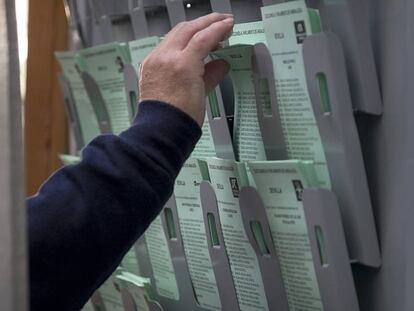 Un hombre recoge la papeleta en una cabina de un colegio electoral en Sevilla.