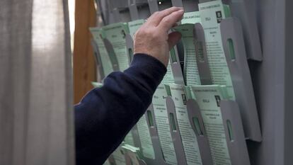 Un hombre recoge la papeleta en una cabina de un colegio electoral en Sevilla.