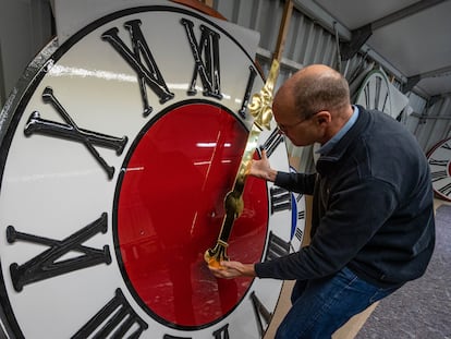 Un hombre sujeta la manecilla de un reloj de torre, en una foto de archivo.