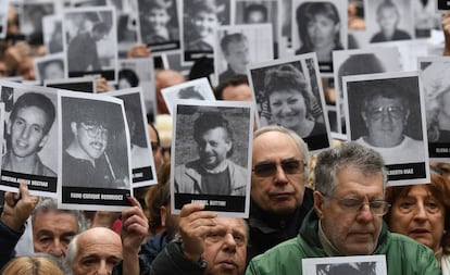 Asistentes al acto de conmemoración del atentado a la AMIA sostienen fotos de las víctimas.