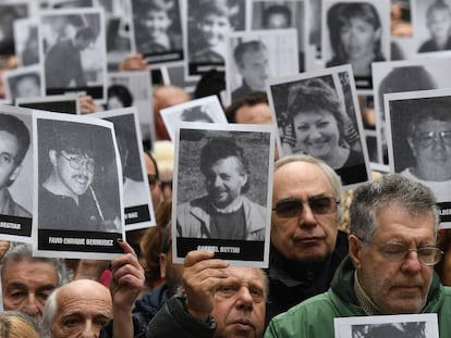 Asistentes al acto de conmemoración del atentado a la AMIA sostienen fotos de las víctimas.