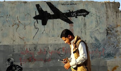 Un yemen&iacute; pasa frente a un graffiti contrario a los bombardeos estadounidenses en el pa&iacute;s.