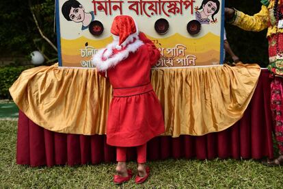 Una niña disfrazada de Papá Noel mira a través de un proyector de cine tradicional durante un evento para conmemorar el día de Navidad en Daca, Bangladesh.