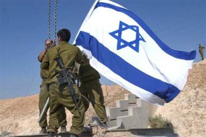 Tres soldados retiran una bandera israelí ayer en una de las entradas de la ciudad de Jericó.