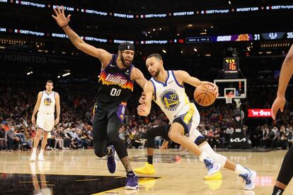 Stephen Curry intenta superar a JaVale McGee durante el partido entre los Warriors y los Suns.
