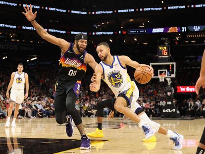 Stephen Curry intenta superar a JaVale McGee durante el partido entre los Warriors y los Suns.