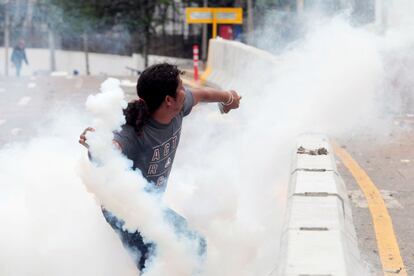 Un manifestante regresa una granada de gas lacrimógeno después de ser atacado por elementos de la policía.