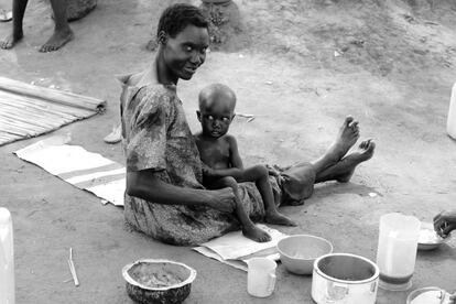 Una mujer da de comer a su hijo al recibir ayuda alimentaria en los campamentos de Uganda.