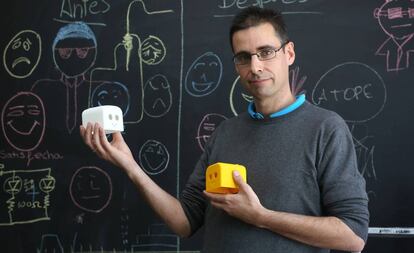 Juan González sostiene dos piezas de robots diseñadas por él mismo.