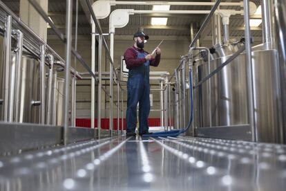 Un empleado monitoriza los procesos automatizados en la fabricación industrial de cerveza.