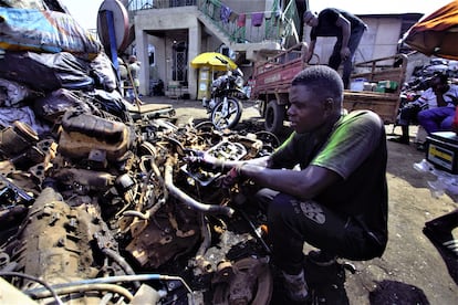 Un trabajador de Agbogbloshie revisa los restos de motores de motocicletas para seleccionar las partes que pueden ser vendidas a los comerciantes locales, que luego las llevan a empresas que los utilizan como insumos. 