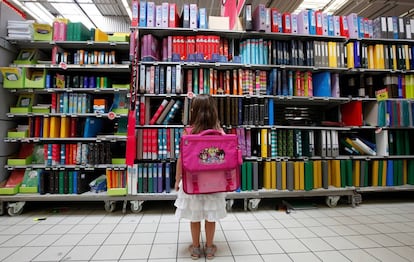 Una niña frente a un estante de venta de útiles escolares en Niza.