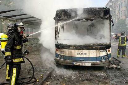 Los bomberos sofocan las llamas del autobús incendiado en San Sebastián en un ataque de violencia callejera.