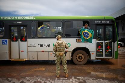 Un partidario de Jair Bolsonaro sostiene una bandera al llegar en autobús a la Academia Nacional de la Policía Federal en Brasilia