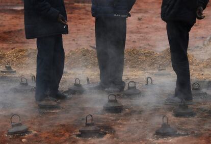 Tres trabajadores se calientan sobre el horno de una fábrica de ladrillos en las afueras de Katmandú (Nepal).