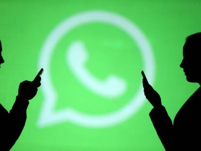 Silhouettes of mobile users are seen next to a screen projection of Whatsapp logo in this picture illustration