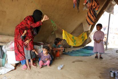 Una mujer y sus hijos son fotografiados en la tienda que ocupan en el campo de desplazados. Estas telas sobre la arena es lo único a lo que pueden llamar hogar. 