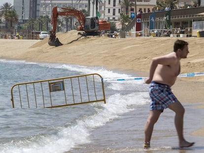 Un ba&ntilde;ista junto a la excavadora en la Barceloneta  