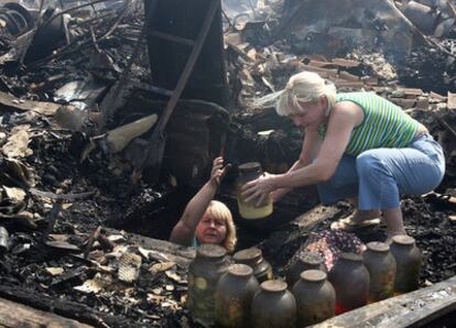 Dos mujeres sacan comida de su casa quemada en Ostafyevo, a 15 kilómetros de Moscú