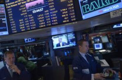 El presidente de la Cámara de Representates estadounidense, John Boehner (en pantalla), habla mientras comerciantes trabajan en la sede de la bolsa de Nueva York.
