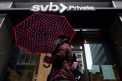 A pedestrian carries an umbrella while walking past a Silicon Valley Bank Private branch in San Francisco, Tuesday, March 14, 2023.