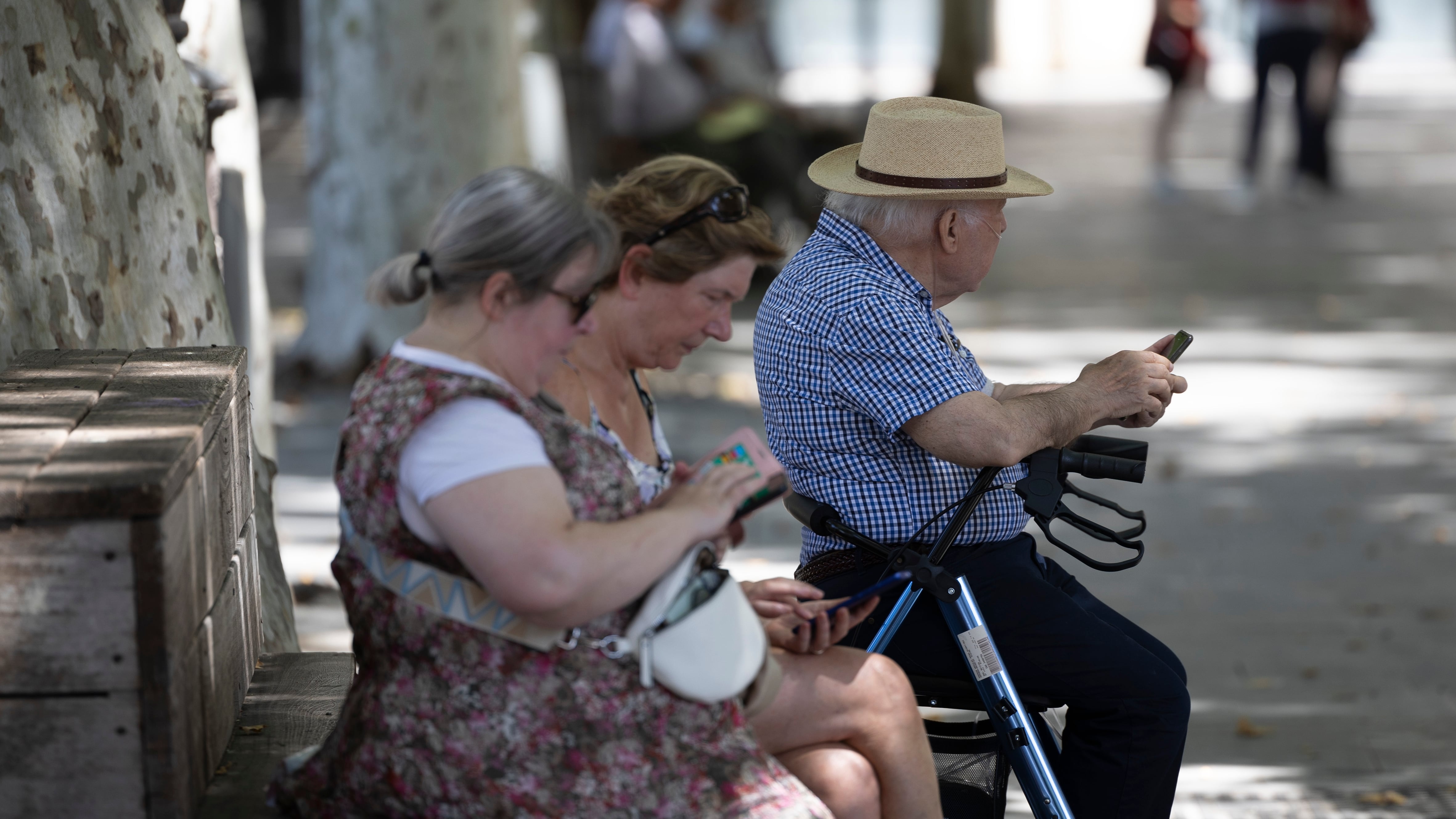 Tres personas mayores miran su móvil en Sevilla en una imagen del 3 de junio de 2024.