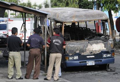 Agentes de polic&iacute;a del El Salvador observan los restos de un autob&uacute;s en el que fueron hallados 14 cuerpos calcinados en 2010.