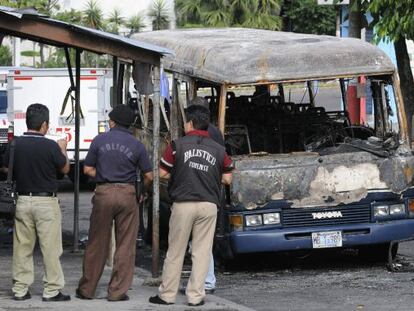 Agentes de policía del El Salvador observan los restos de un autobús en el que fueron hallados 14 cuerpos calcinados en 2010.