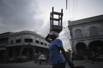 Un vendedor transporta un taburete por una calle de Puerto Príncipe (Haití).