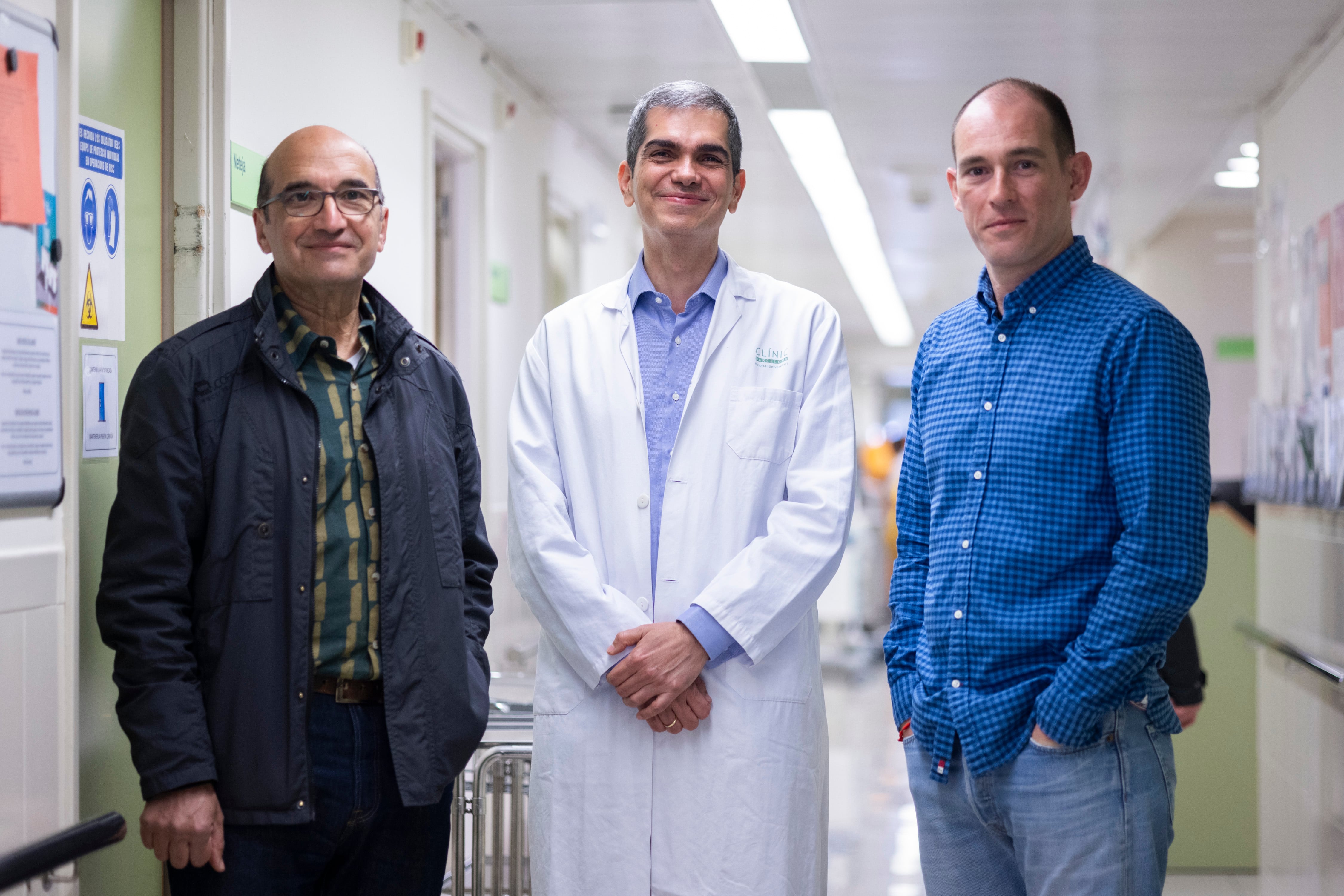 Los pacientes Juan Carlos del Val (izq.) y David Zafra (dcha.), junto al hematólogo Julio Delgado, en los pasillos del Clínic.
