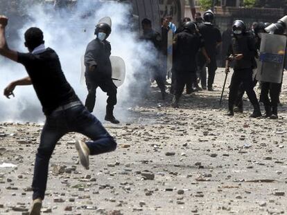 Un manifestante lanza una lata de gas lacrim&oacute;geno contra un polic&iacute;a en los disturbios junto a la embajada de EE UU en El Cairo.