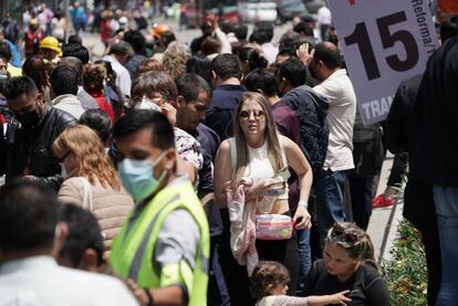 La gente evacuada de los edificios se acomoda sobre Paseo de la Reforma, en el centro de Ciudad de México.
