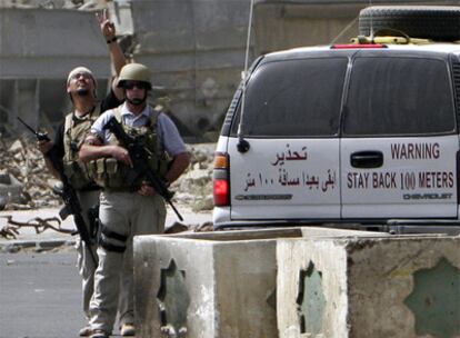 Unos agentes privados vigilan el escenario de un atentado con bomba en Bagdad en julio de 2005.