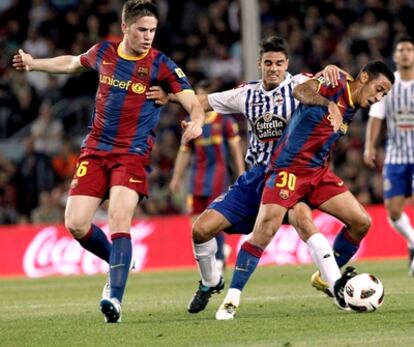 Thiago y Fontàs del Barcelona luchan con Juan Rodríguez por un balón.