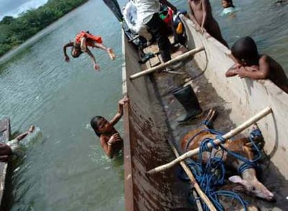 Un grupo de niños miskitos juega alrededor de una barca con un venado recien cazado en el río Coco, en Nicaragua.