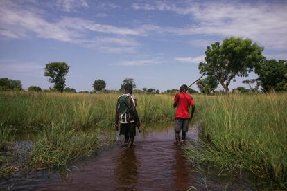 Jóvenes armados caminan por un campo inundado en la aldea de Anyidi a finales de septiembre.