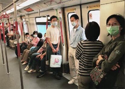 Viajeros del metro de Hong Kong se protegen con una máscara para evitar el contagio de la neumonía.