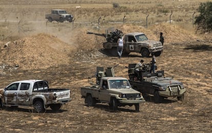 Varios vehículos armados lanzan proyectiles sobre el aeropuerto de Trípoli. Los vehículos han sido pintados con una "x" de color rojo para que los aviones leales al GNA no les ataquen. Los combatientes llevan unos lazos rojos para que los francotiradores del mismo bando no les confundan con el enemigo.