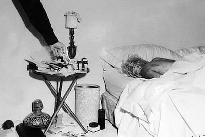 Imagen inédita del cadáver de Marilyn Monroe en el dormitorio de su casa. Un policía, probablemente el sargento Jack Clemmons, señala las pastillas que provocaron la muerte de la actriz.