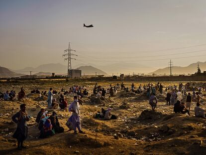 Un avión de transporte militar parte mientras decenas de afganos que quieren salir del país tras la llegada de los talibanes esperan en los alrededores del aeropuerto de Kabul en agosto de 2021.