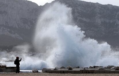 Un hombre toma una fotografía cuando las olas golpean el muelle de Marsella después de que la tormenta Eleanor golpeara a Francia.
