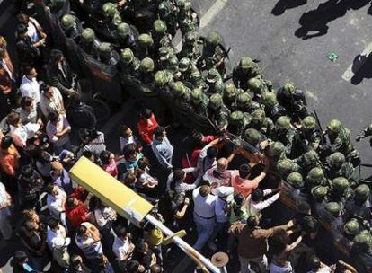 Manifestantes tratan de romper hoy la línea de policías desplegados en una de las calles de la capital de la provincia china de Xinjiang