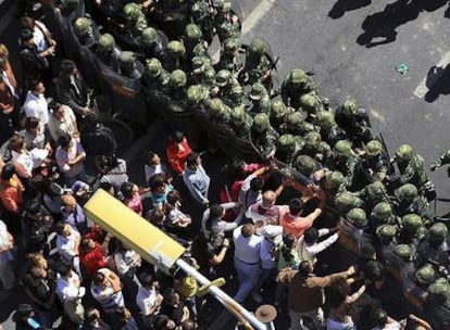 Manifestantes tratan de romper hoy la línea de policías desplegados en una de las calles de la capital de la provincia china de Xinjiang