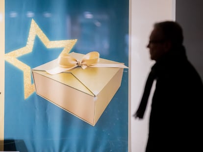 Un hombre pasa por un escaparate con una imagen de un regalo de Navidad en la calle.